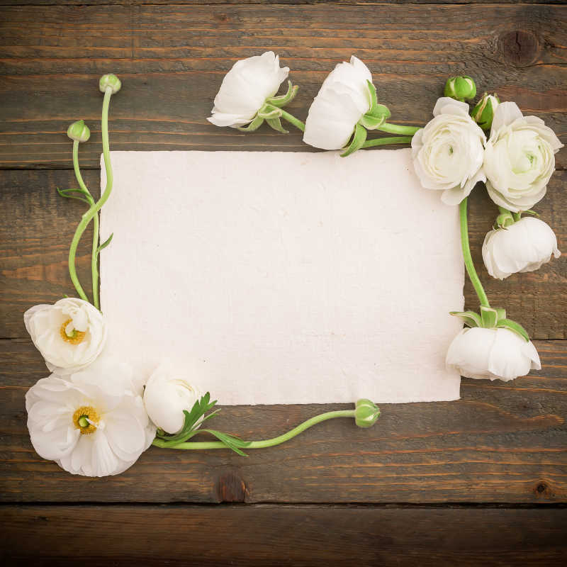 纸明信片和白色花朵在木制的背景俯视图