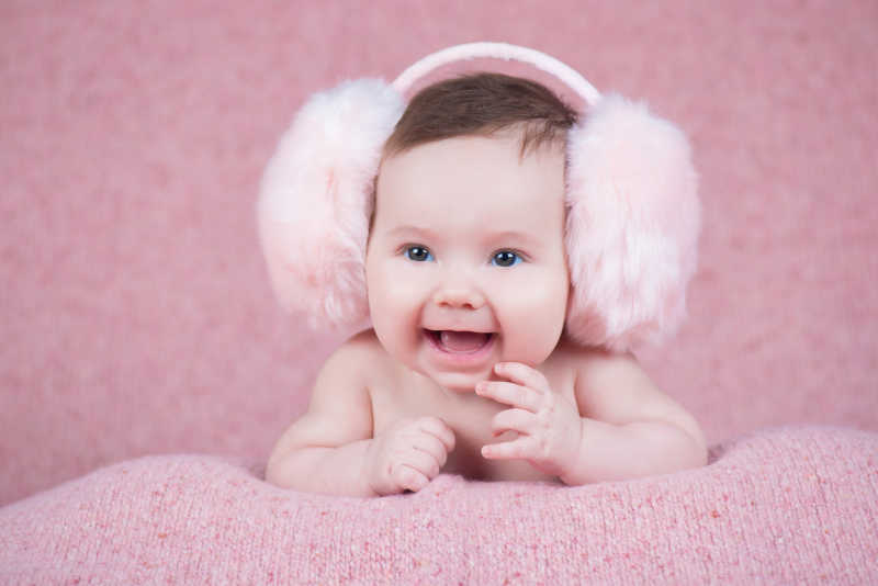 美丽的小女孩穿着粉红色温暖的耳机