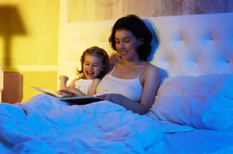 孩子和妈妈半倚在床头看书