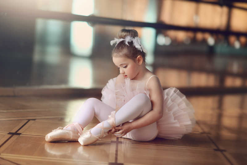 大厅里的坐在地上的穿芭蕾舞鞋的小女孩