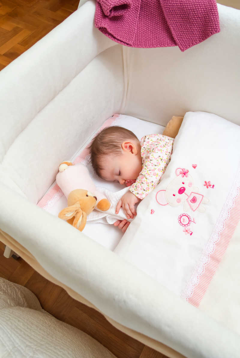 可爱的小女孩睡在婴儿床含着奶嘴抱着毛绒玩具