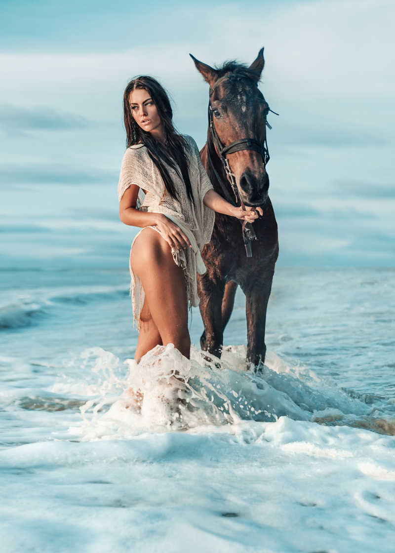站在海边的性感美女与雄伟的马匹
