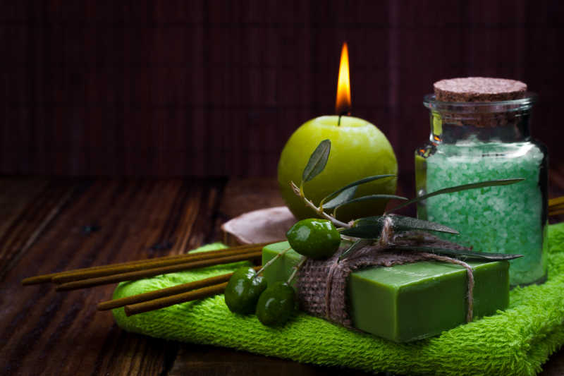 绿色毛巾上的橄榄肥皂蜡烛和浴盐