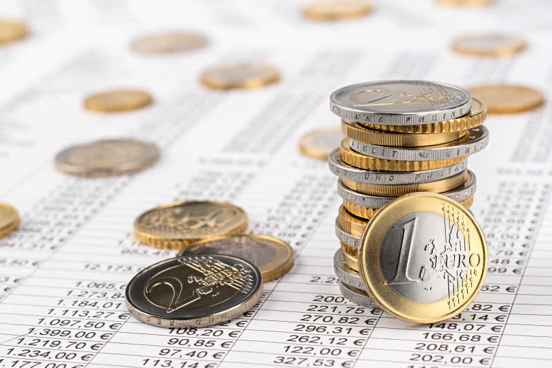 欧元硬币堆在企业财务数据表上