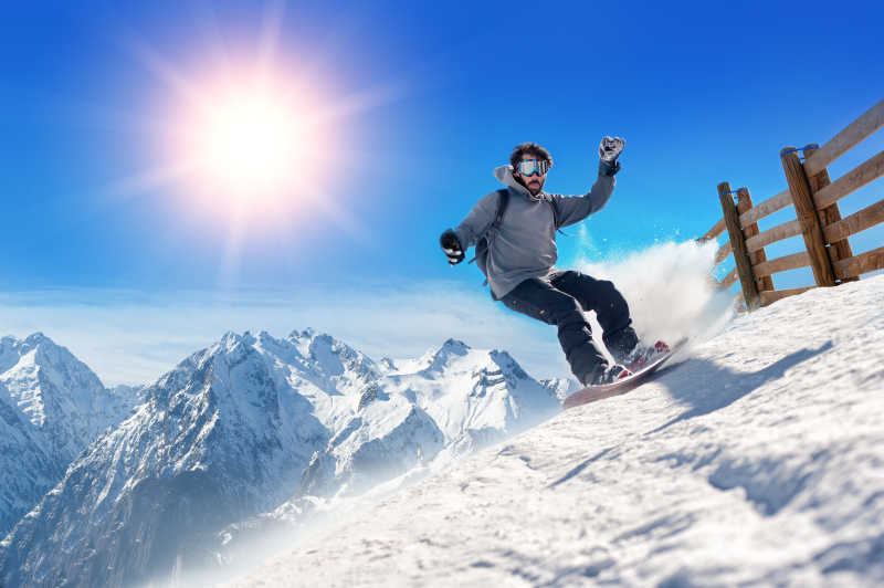 滑雪的人拿着滑雪板在山上的空气背景的跳跃