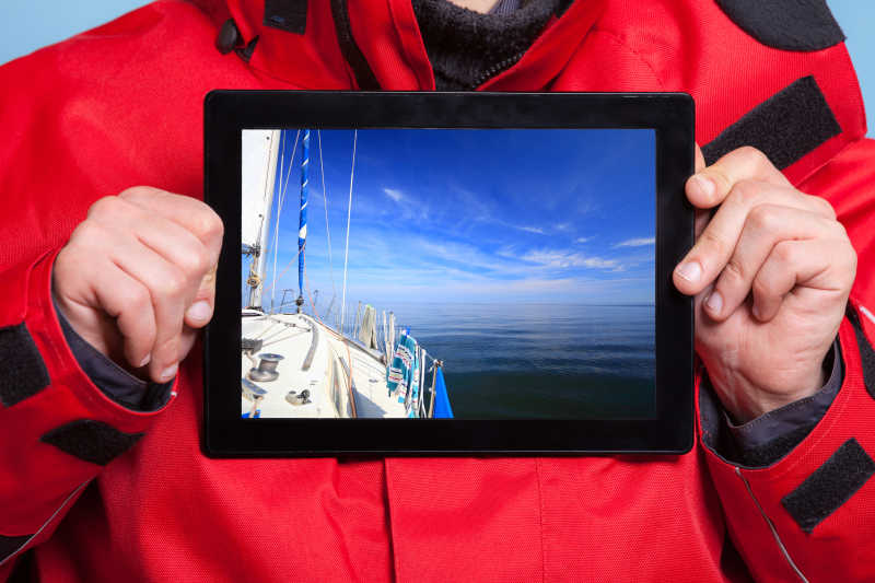 男性双手捧着iPad与游艇帆船照片特写