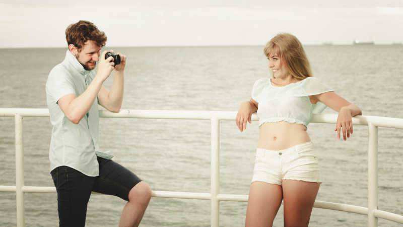 热恋中的年轻情侣在码头上拍照