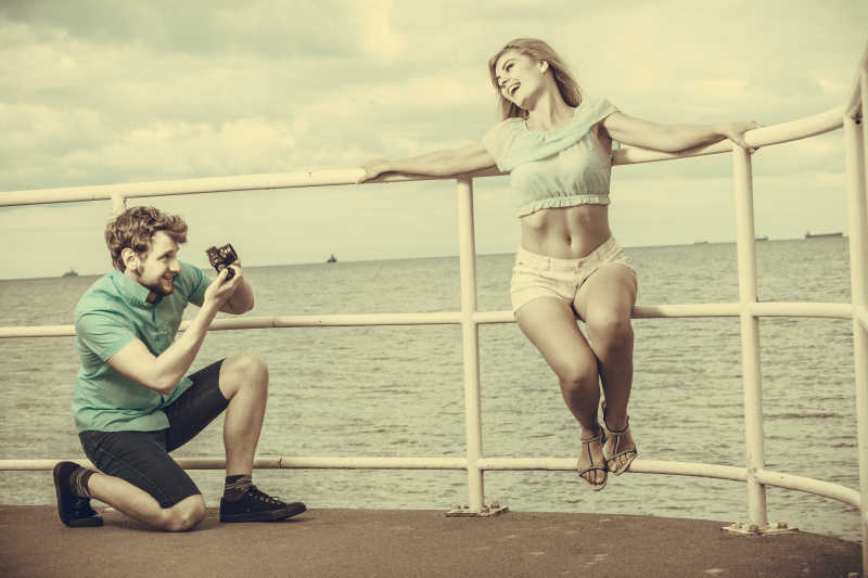 年轻情侣在海边码头拍照