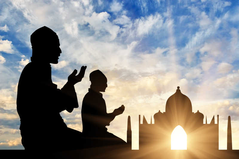 两个男人在日落时分清真寺背景下祈祷