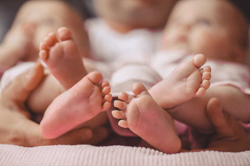 母亲手中可爱的双胞胎新生儿的脚丫
