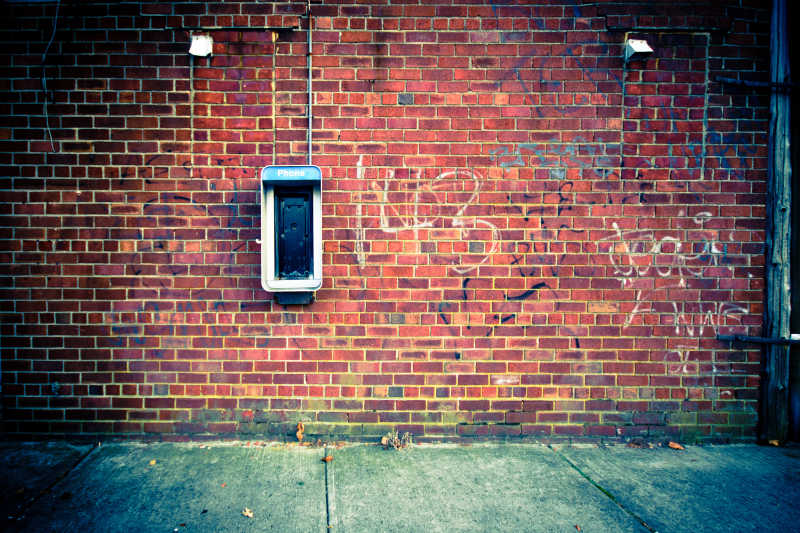 老式公共电话与砖墙