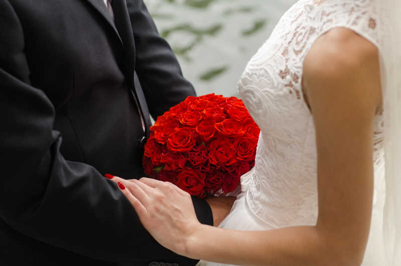 新娘新郎与新娘手里的红玫瑰捧花
