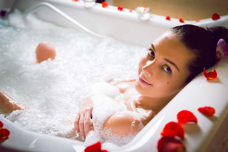 浴缸里放有玫瑰花瓣泡澡的美女