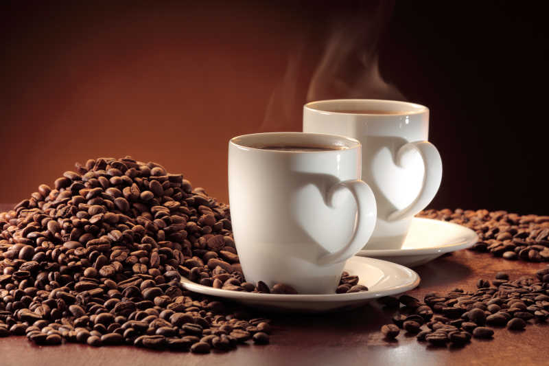 棕色背景下两杯热气腾腾的咖啡和一堆咖啡豆