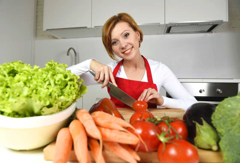 家庭厨房里快乐的女人准备做蔬菜沙拉