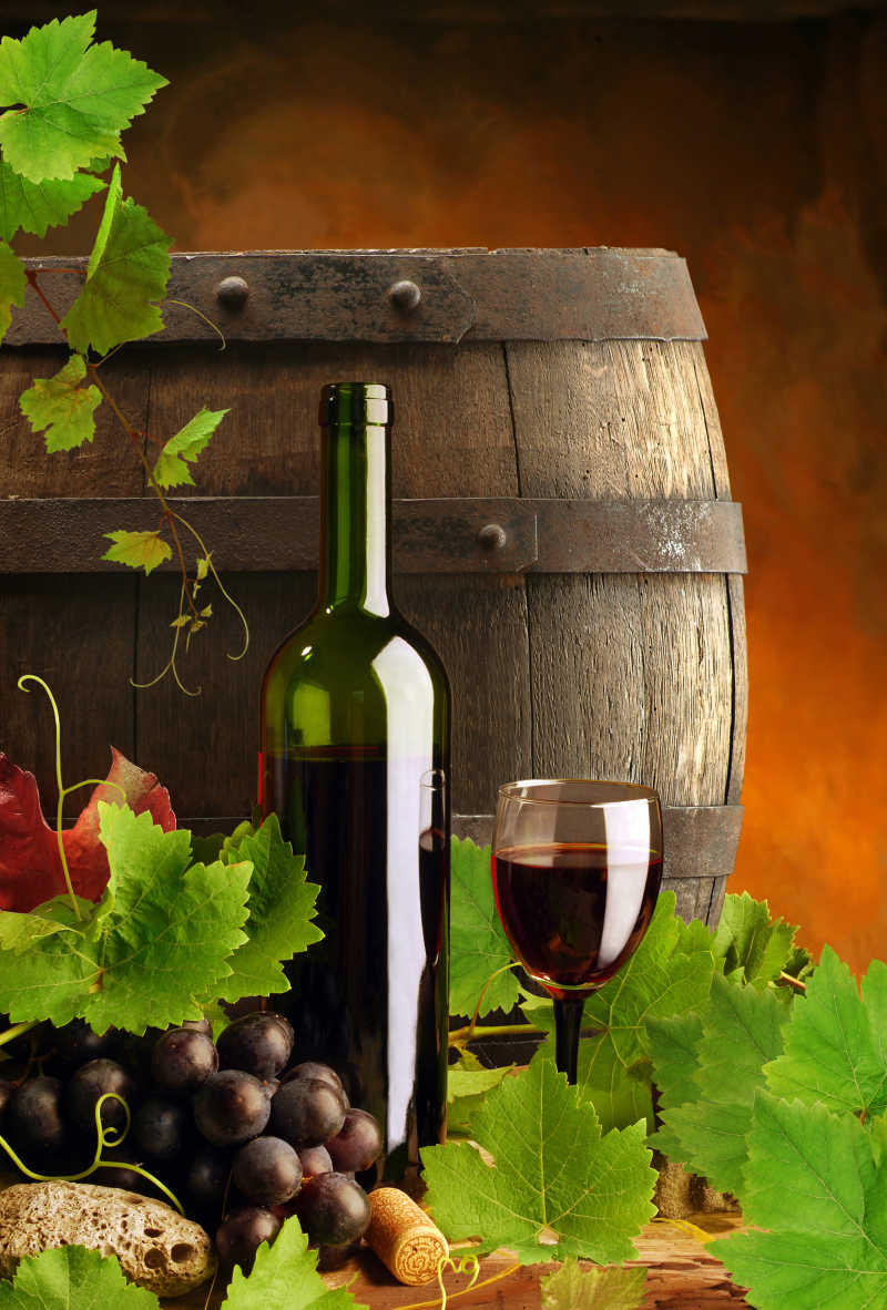 新鲜葡萄和装满葡萄酒的木桶酒瓶以及杯子