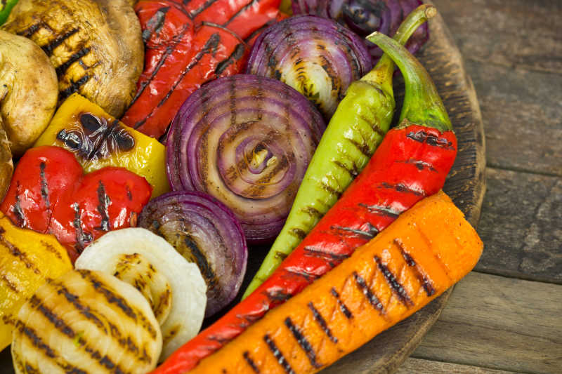 木质桌面上木盘子里烤好的蔬菜