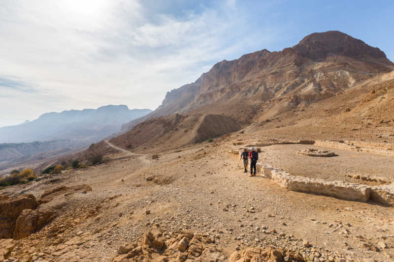 站在以色列犹太沙漠的古遗迹旁边的考古学家