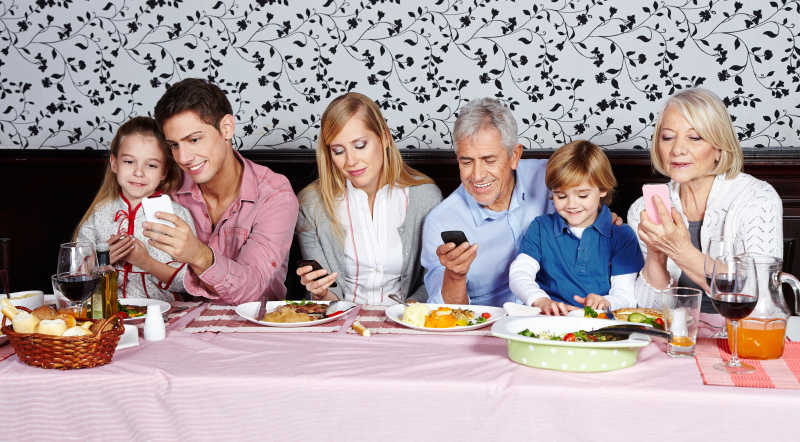 家庭聚餐时全部沉迷于玩手机的一家人