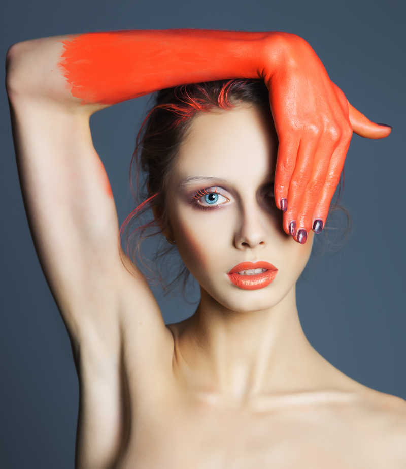 将手涂成橙色遮住眼睛的美女创意肖像