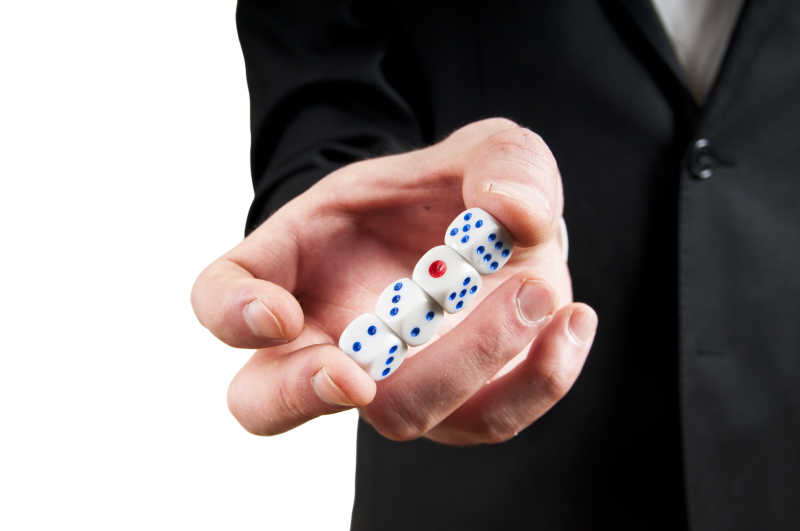 男子手持白色赌场骰子