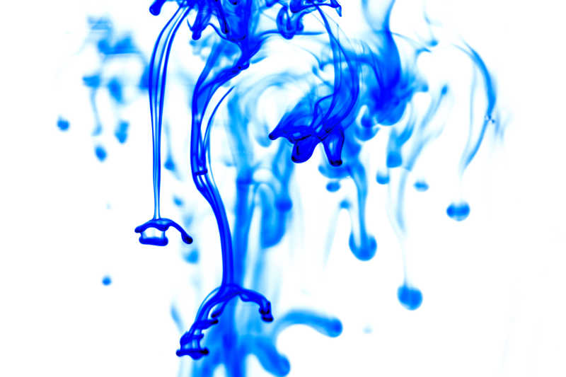 白色背景上的滴入水中的蓝色墨水