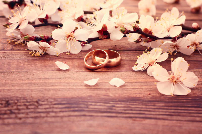 木制桌面上的花瓣和结婚对戒