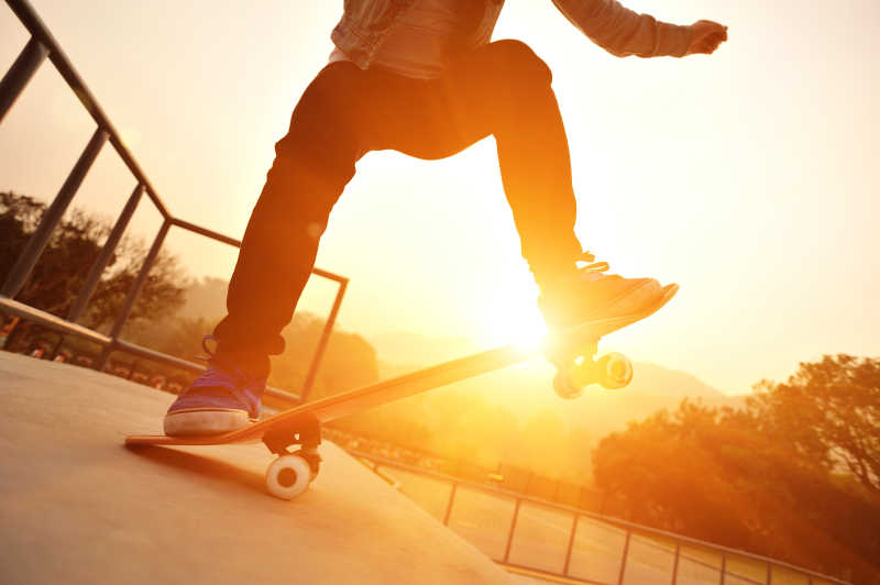 夕阳下玩滑板的年轻人特写