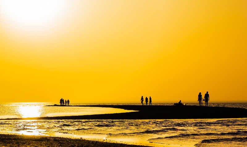 日落时分在海滩上散步的人剪影
