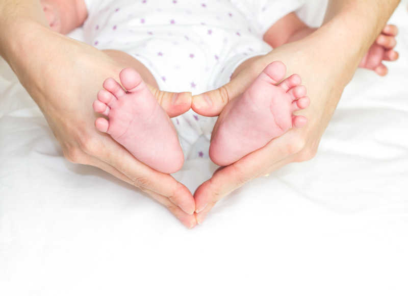 母亲的手握着婴儿的脚形成一个心框