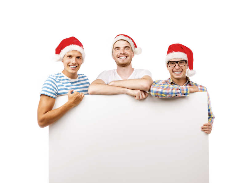 空白横幅后面的戴着圣诞帽的三个年轻人