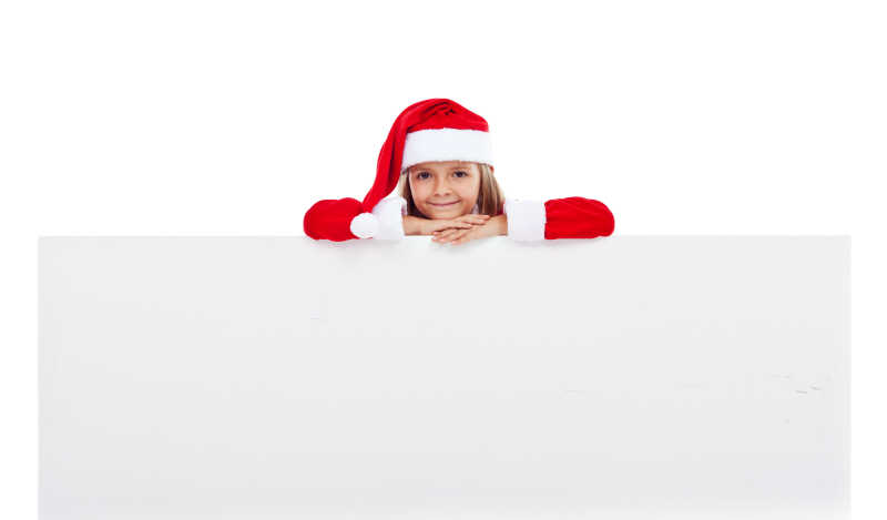 趴在白色空白横幅上戴着圣诞帽的小女孩