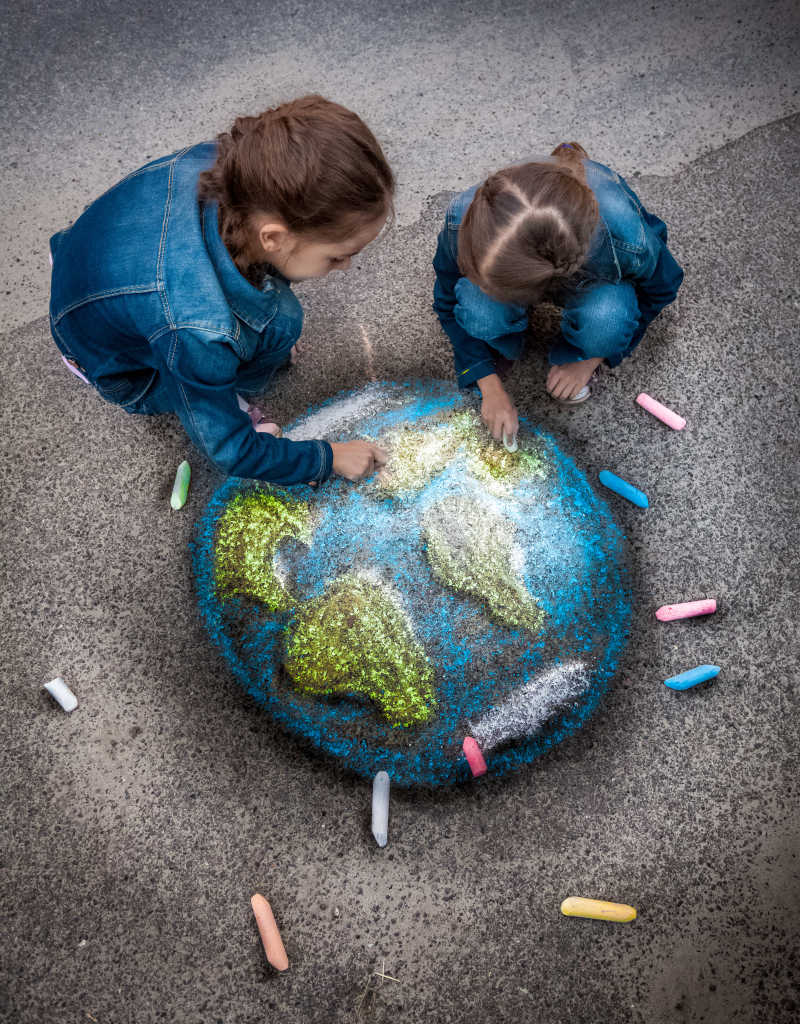 两个女孩用粉笔在地上画地球特写