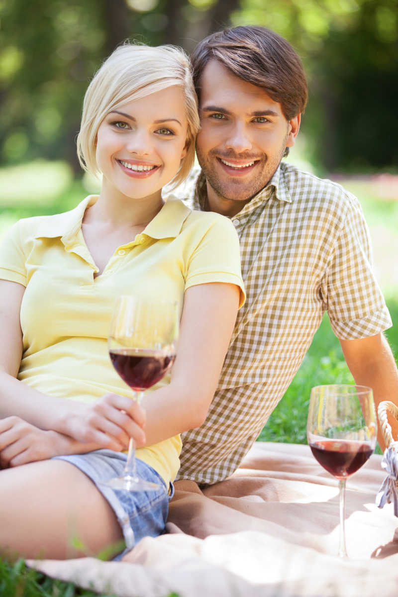 快乐的年轻夫妇在野餐上喝酒