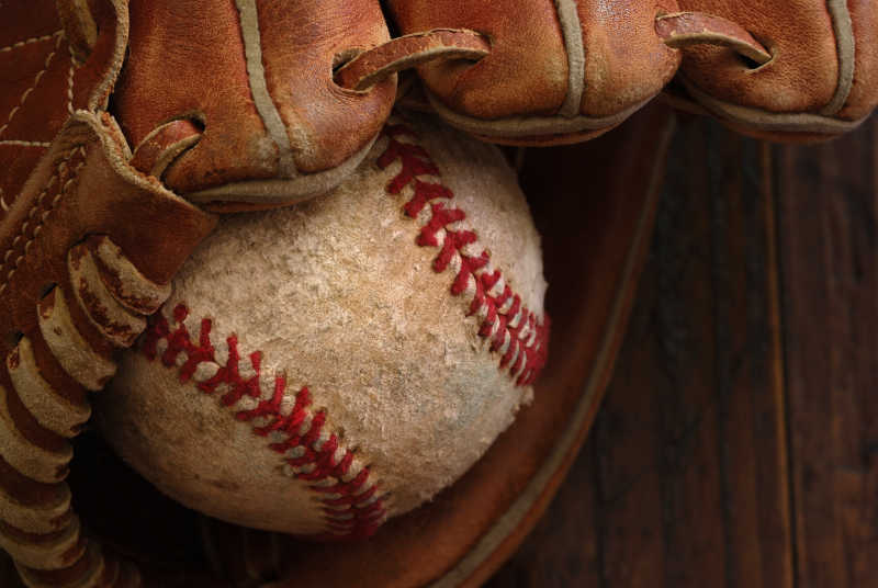旧棒球手套与风化棒球木背景