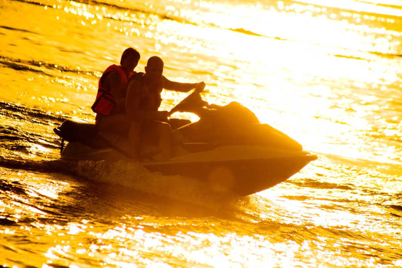 夕阳下驾驶着摩托艇的情侣