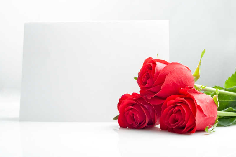 空白的贺卡前放着三朵红玫瑰