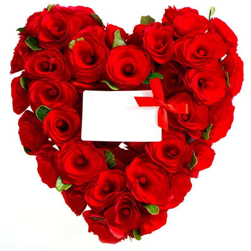 玫瑰组成的心型图案上放着一张空白贺卡