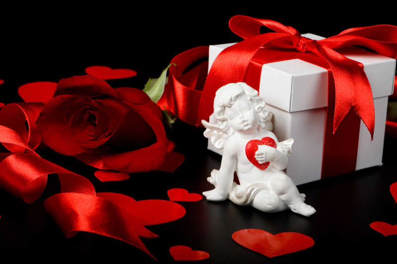 情人节礼物前堆放着玫瑰和丘比特雕像