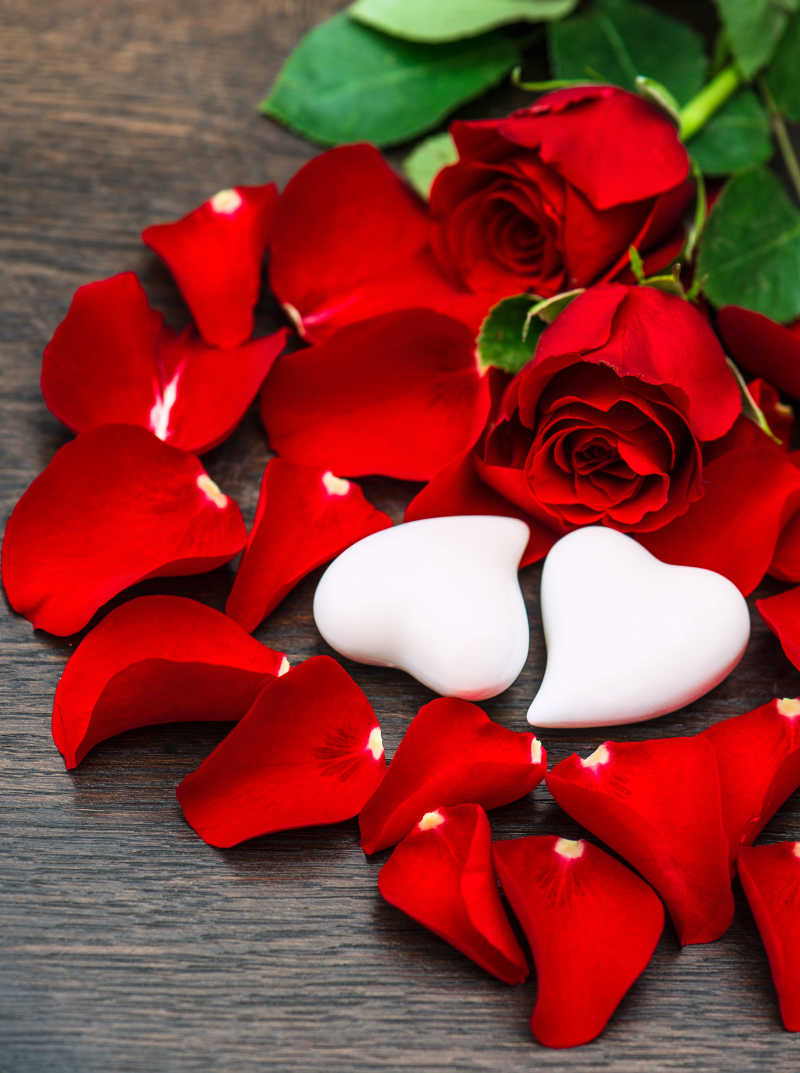 玫瑰花瓣点缀的两颗白色的心型装饰
