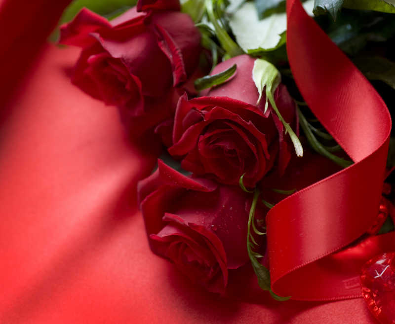 红色丝绸上放着三朵绯红色的玫瑰