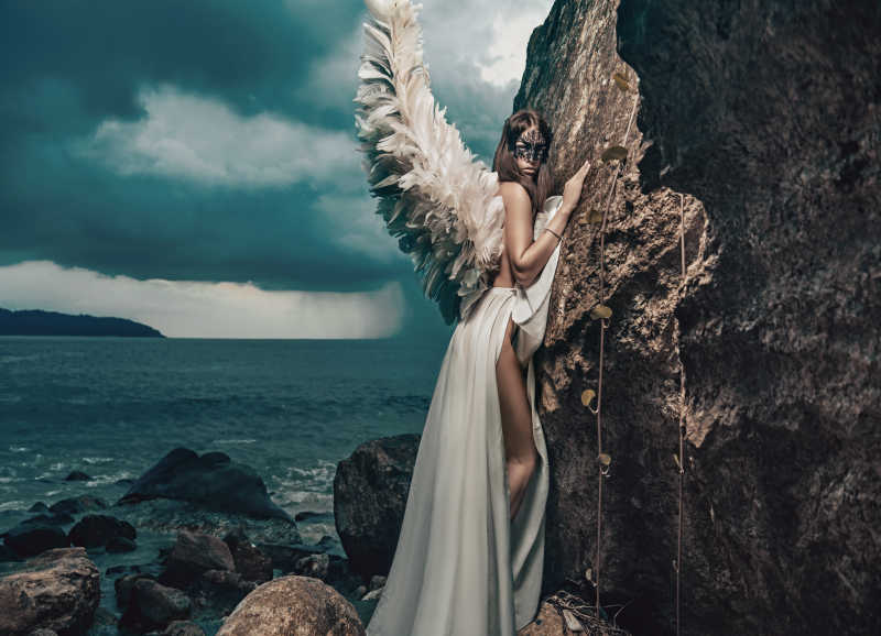 带着翅膀的美女天使趴在岩石上
