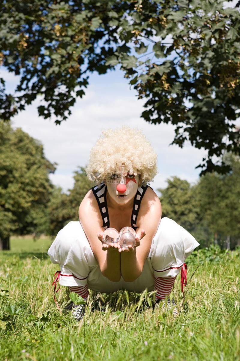 一个小丑在草地上玩水晶球