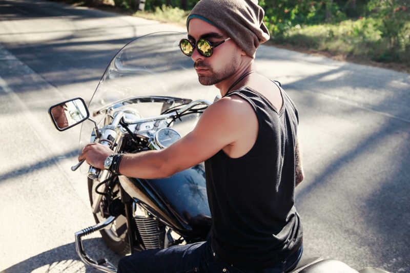 骑在摩托车上的男人戴着帽子和墨镜