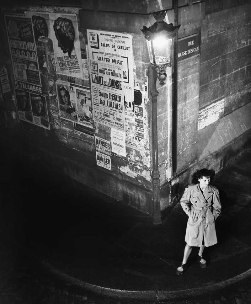 黑夜里女子等在贴满复古旧广告的墙边