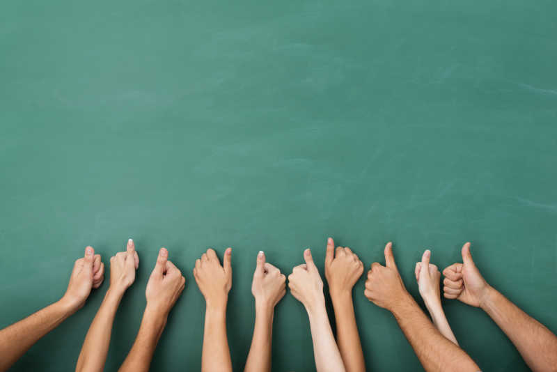 绿色黑板上一组人竖起大拇指的手势