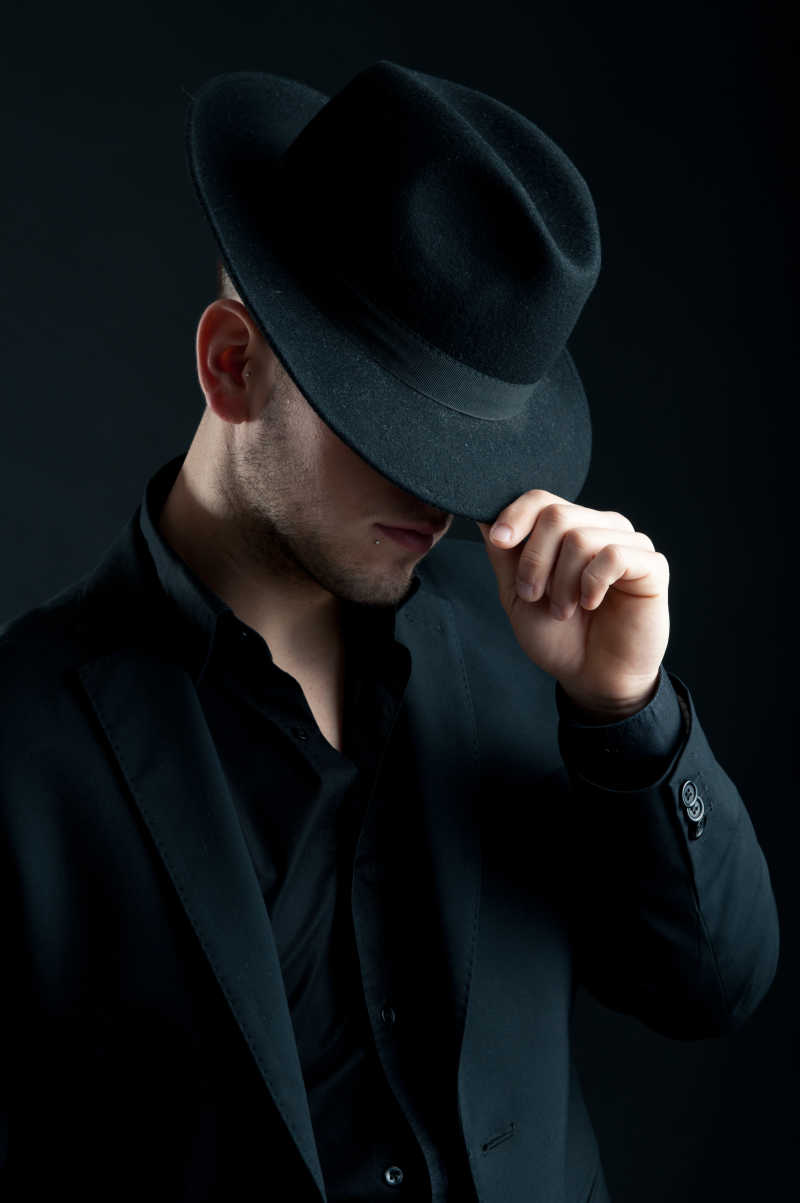 黑色背景下戴帽子的时尚男人
