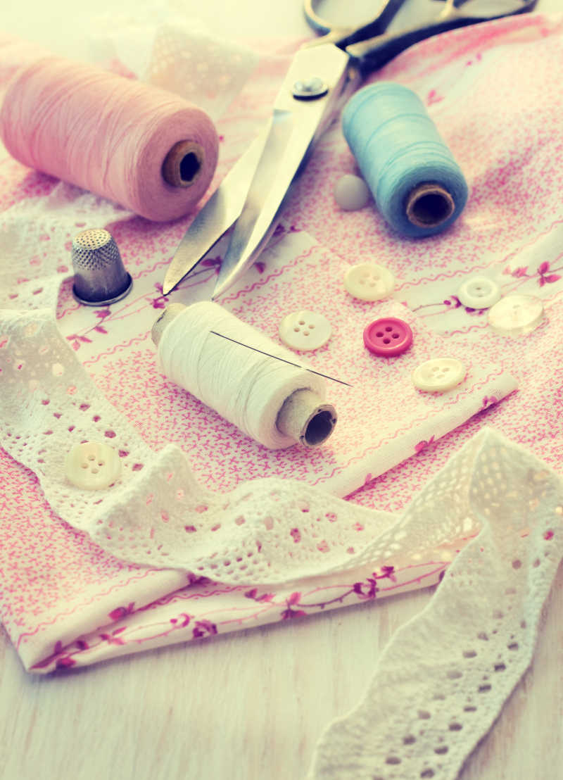 粉色布料上的剪刀 针 钮扣等缝纫配件