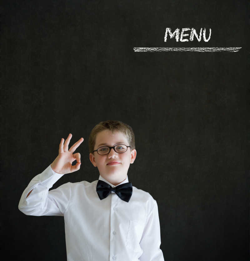 男孩在黑板上粉笔写的菜单商业概念