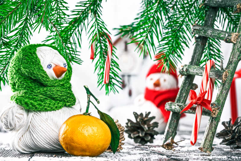 圣诞树下的手工纱线雪人和新鲜的橘子